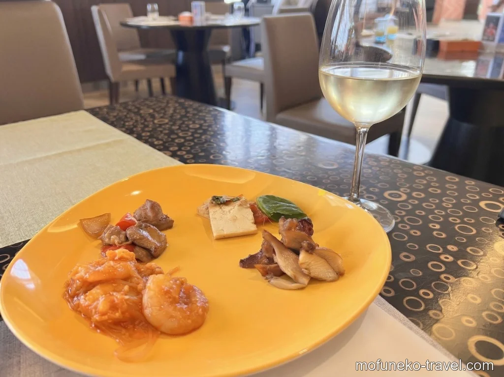 エビチリやきのこ、お肉などのおつまみが盛られた黄色いお皿