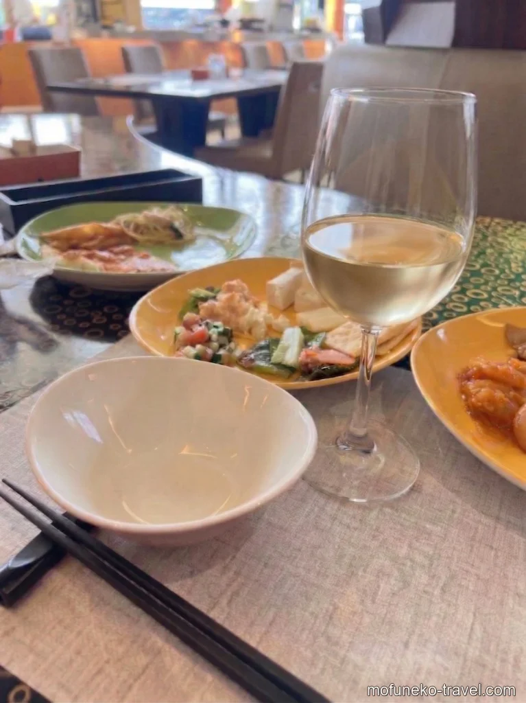 白ワインのグラスとサラダやチーズが盛られたお皿